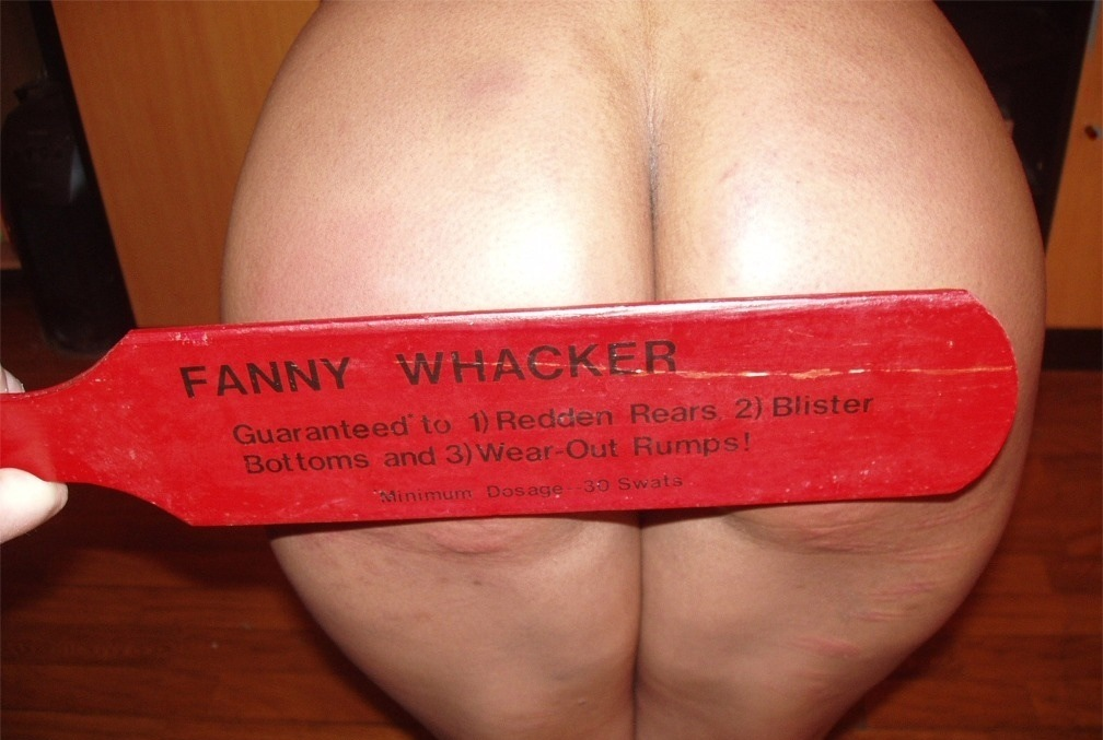 home-made novelty paddle the fanny whacker being applied to a female derriere